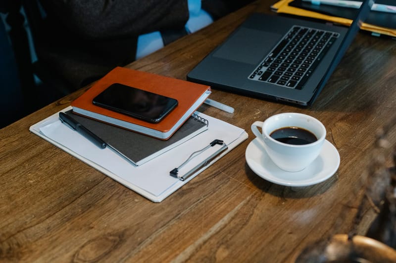 A coordinator's tidy desk — notebook, phone, and coffee at the ready
