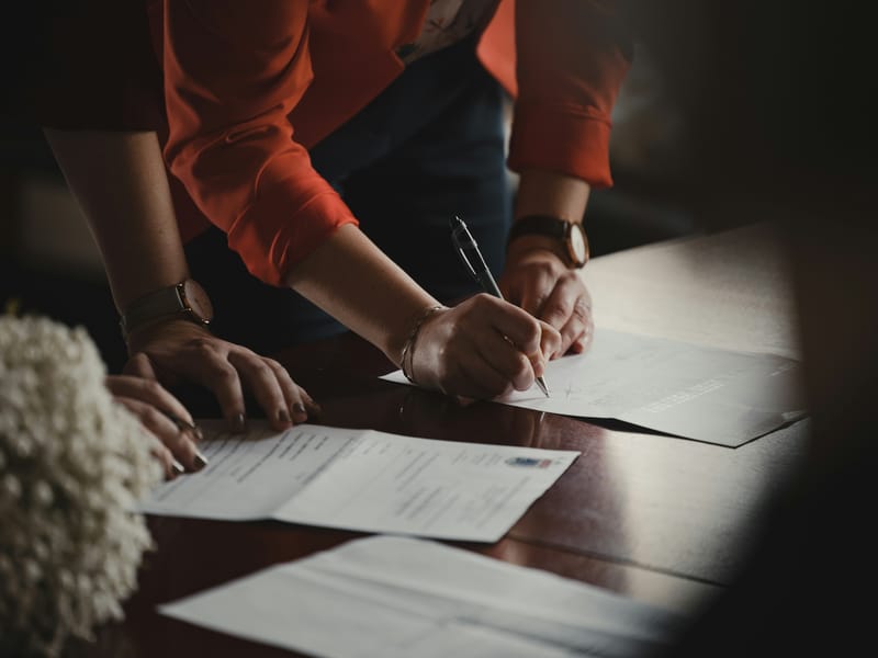 Agent and clients signing the closing paperwork at a desk